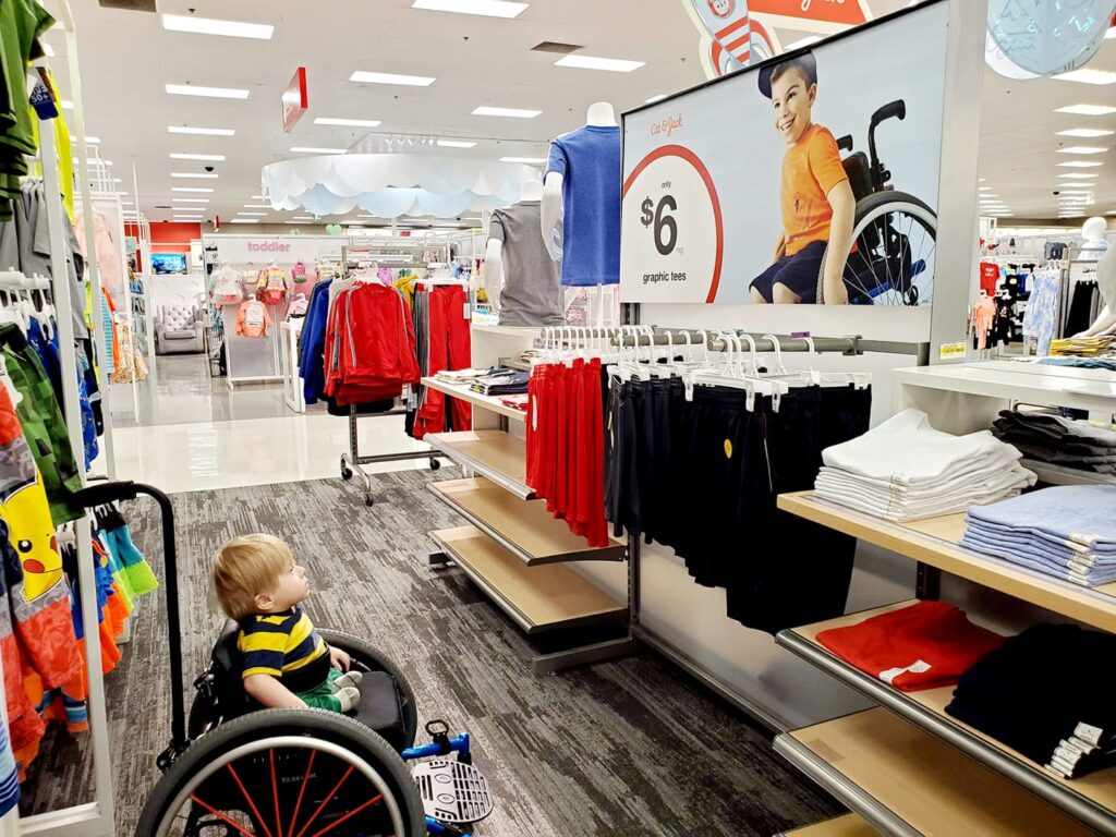 Two-year-old Ollie looks up in awe at a display at Target featuring a young boy who uses a wheelchair, just like he does.